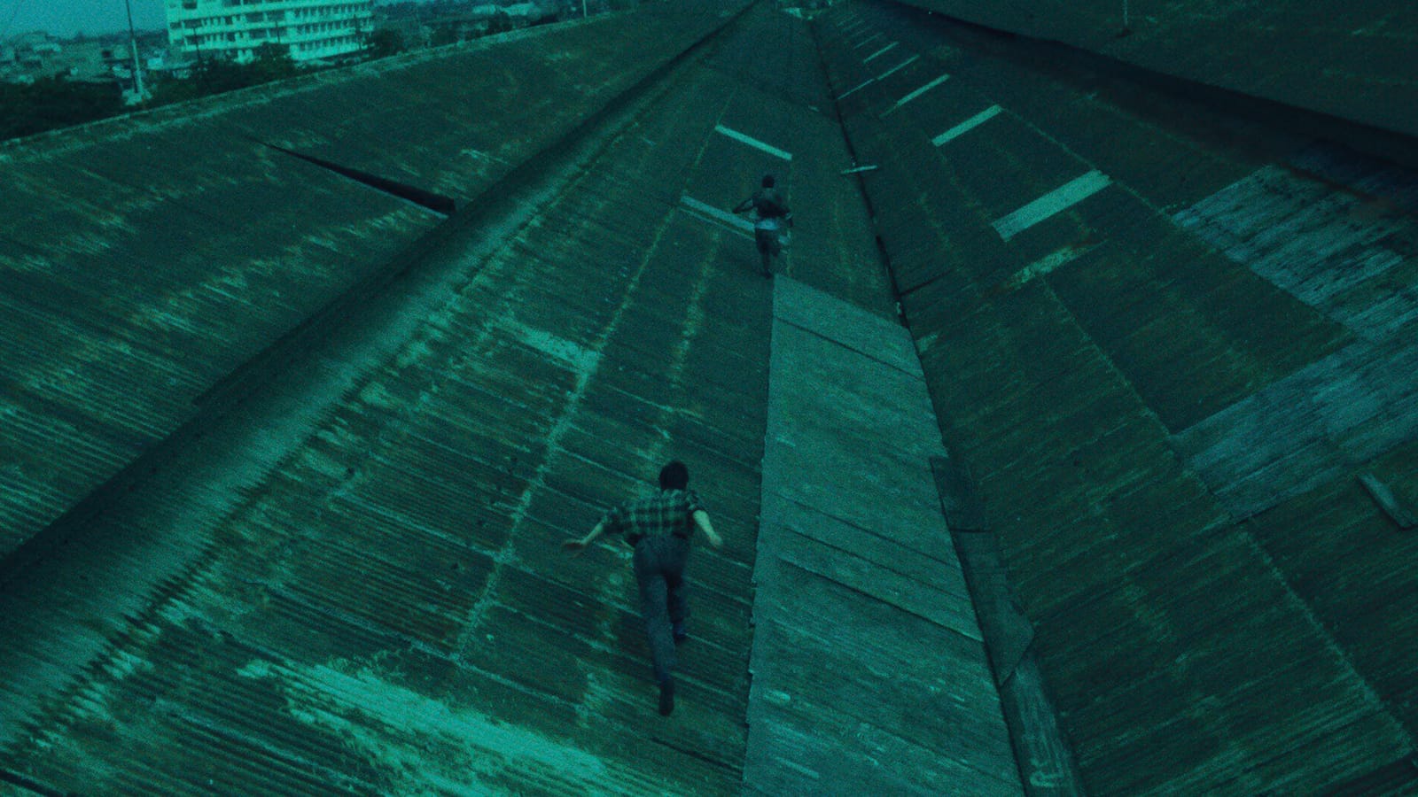 Two men run after each other on a tiled roof